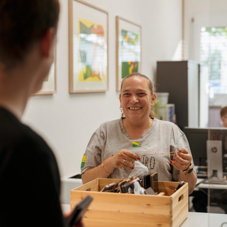 Eine lächelnde Frau hält eine Holzschachtel mit Gegenständen.