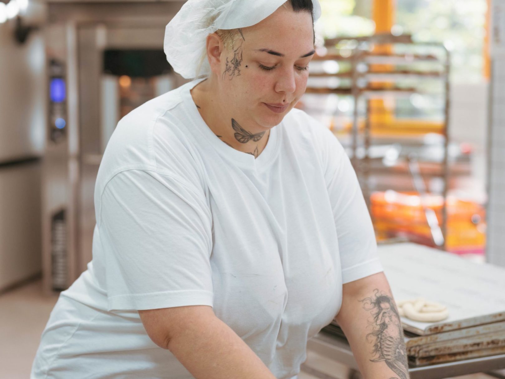 Eine Frau mit Tattoos rollte Teig in der Bäckerei.