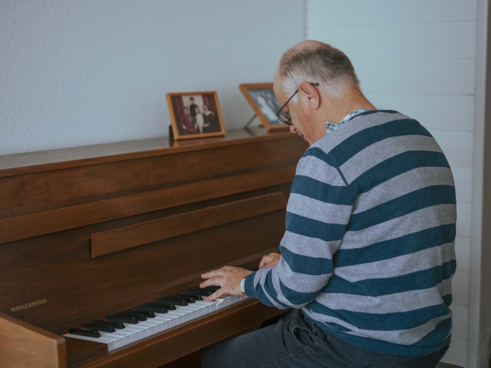 Ein älterer Mann sitzt an einem Klavier und spielt.