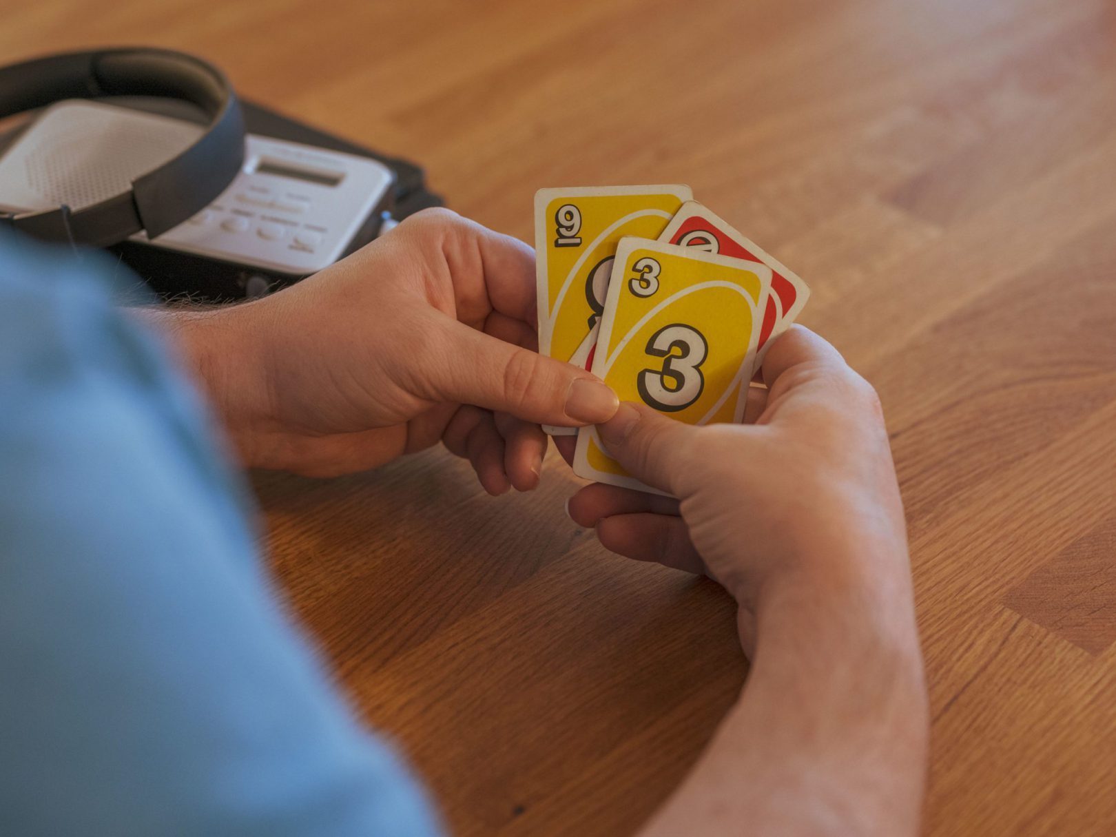 Eine Person sitzt am Tisch und hält Uno-Karten in den Händen.