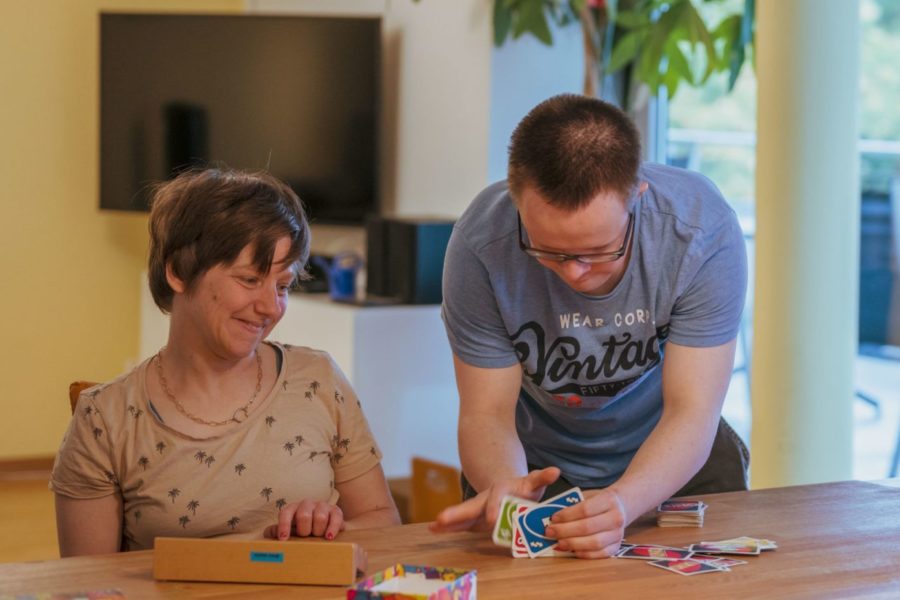 Drei Bewohner sitzen an einem Tisch und spielen mit Uno-Karten.