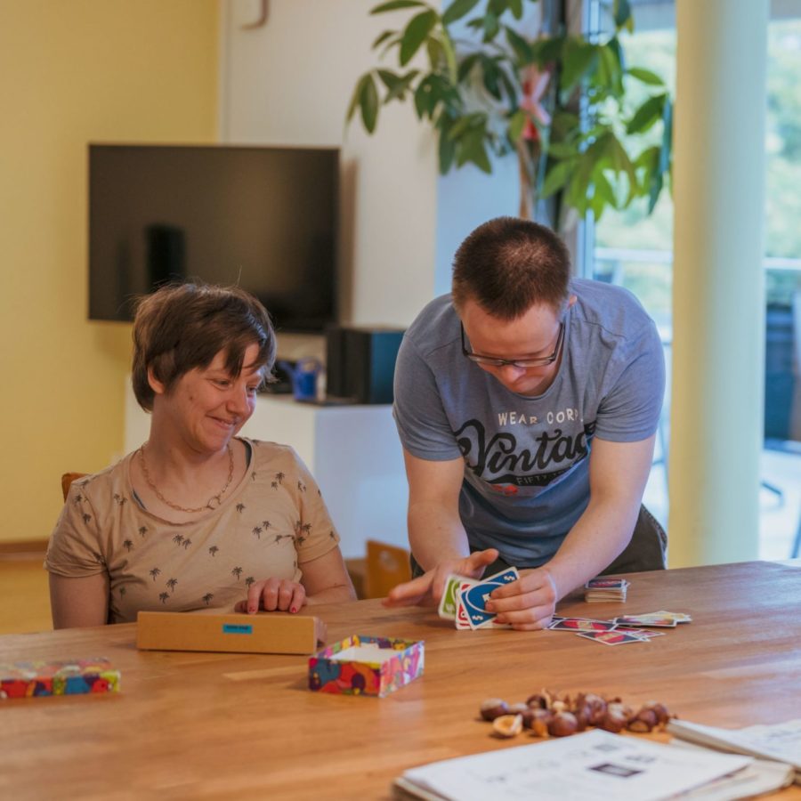 Drei Bewohner sitzen an einem Tisch und spielen mit Uno-Karten.