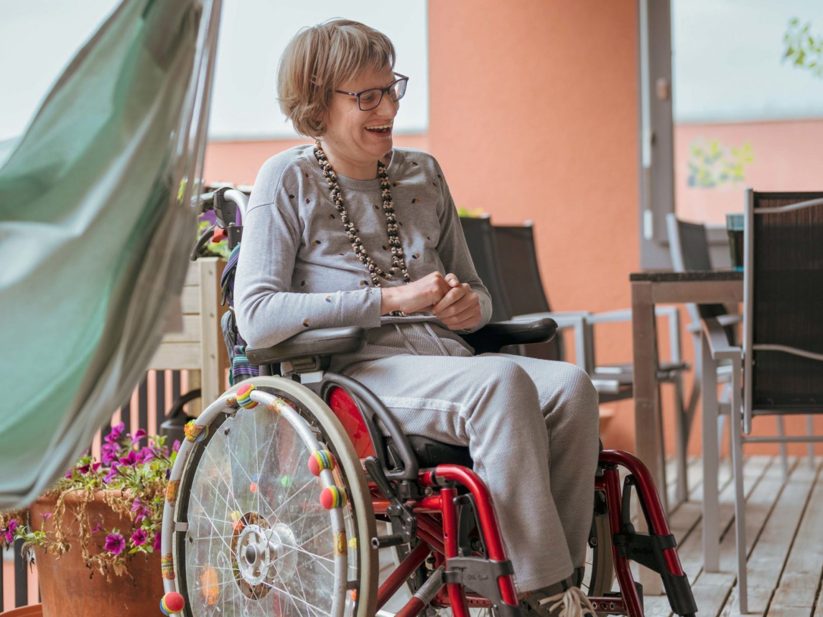 Eine Frau im Rollstuhl sitzt auf der Terrasse vom Wohnhaus Wyden.
