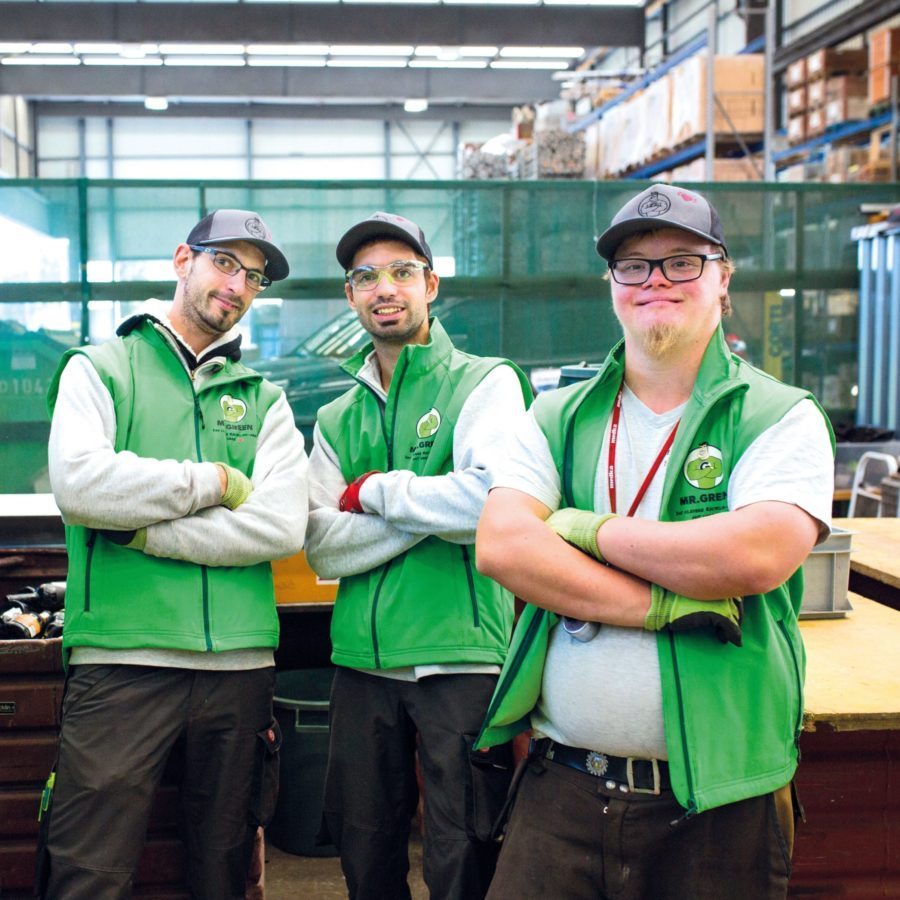 Drei Männer mit Arbeitskleidung aus unserem Mr. Green Recycling Team stehen da mit verschränkten Armen.