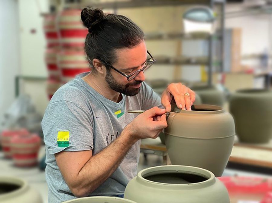 Ein Mann mit Brille arbeitet an einer Urnen-Töpferei.