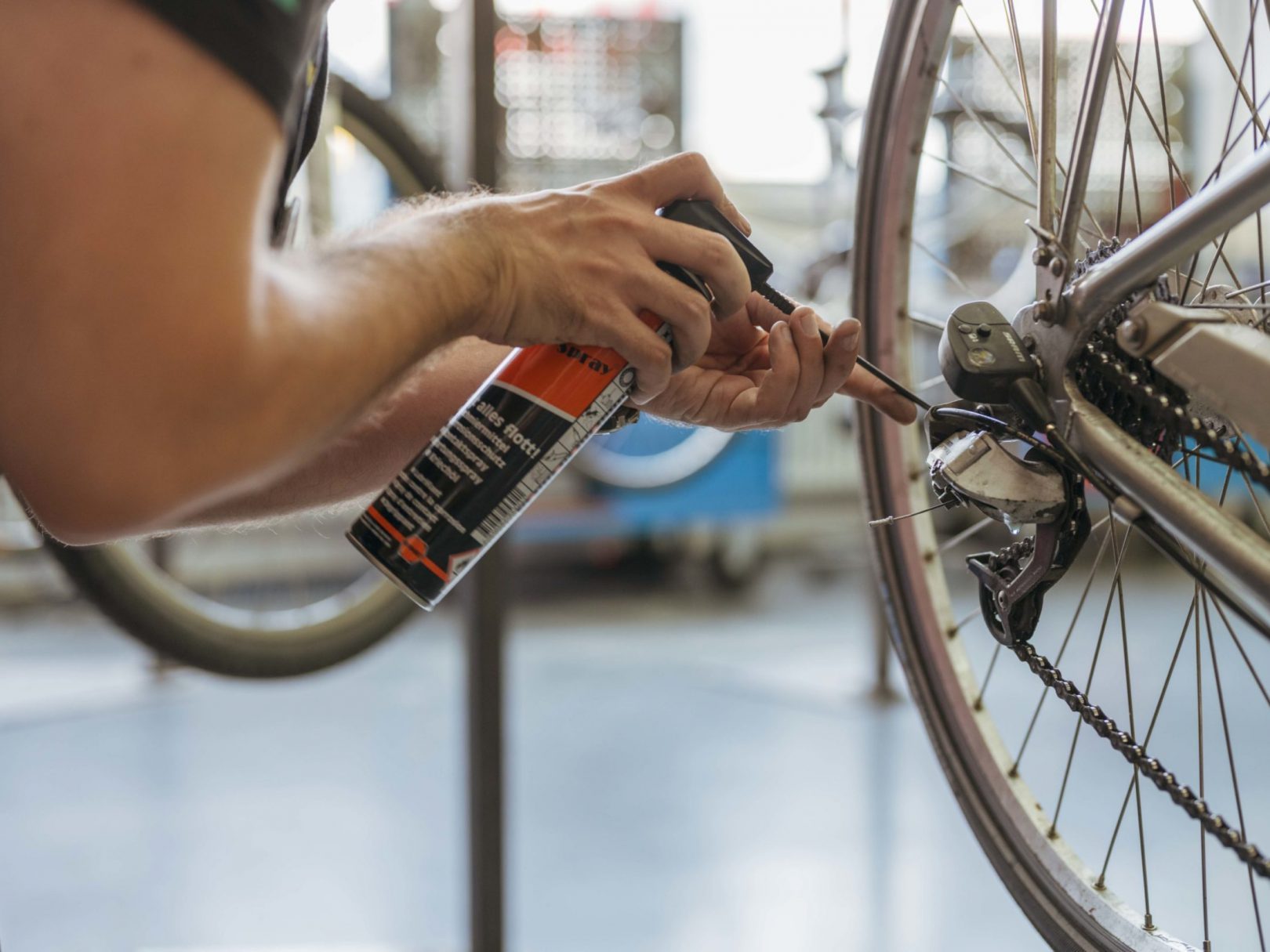 Ein Mann repariert in unserer Velowerkstatt ein Fahrrad mit einer Flasche.