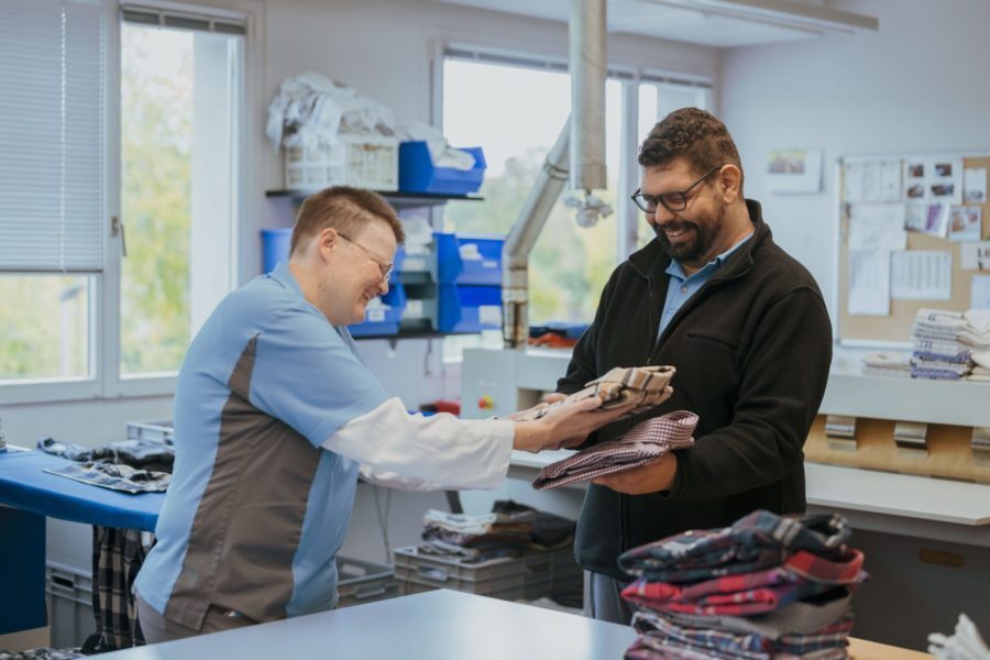 Zwei Personen in der Wäscherei stapeln zusammengefaltete Hemden.