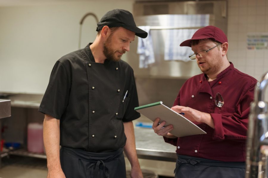 Ein Angestellter und ein Zivildienst der Brühlgut Stiftung studieren eine Liste in der Küche des Restaurants Neumarkt.