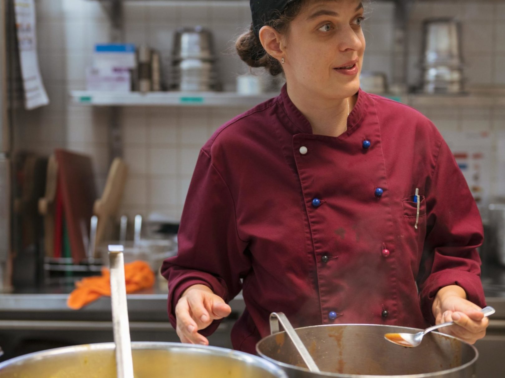 Eine Frau hält einen Kochlöffel und kocht in der Küche des Restaurants Neumarkt.