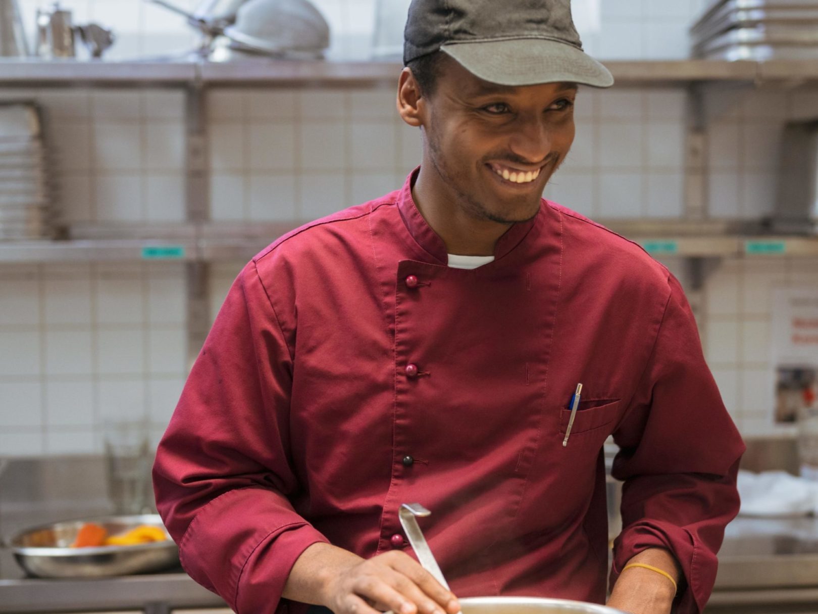 Ein Mann steht in der Küche des Restaurants Neumarkts vor einem Kochtopf und lacht.