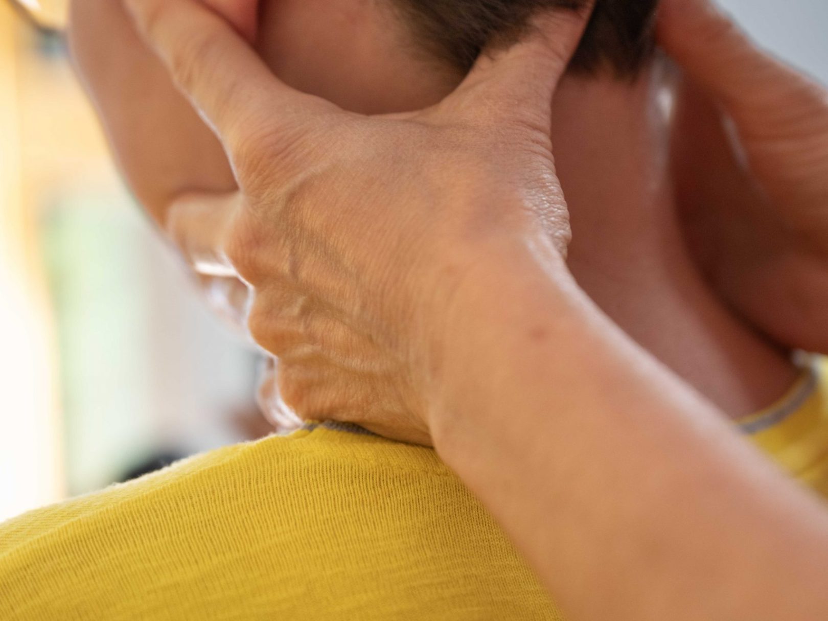 Eine Frau wird in der Physiotherapie am Kopf gehalten und stabilisiert.