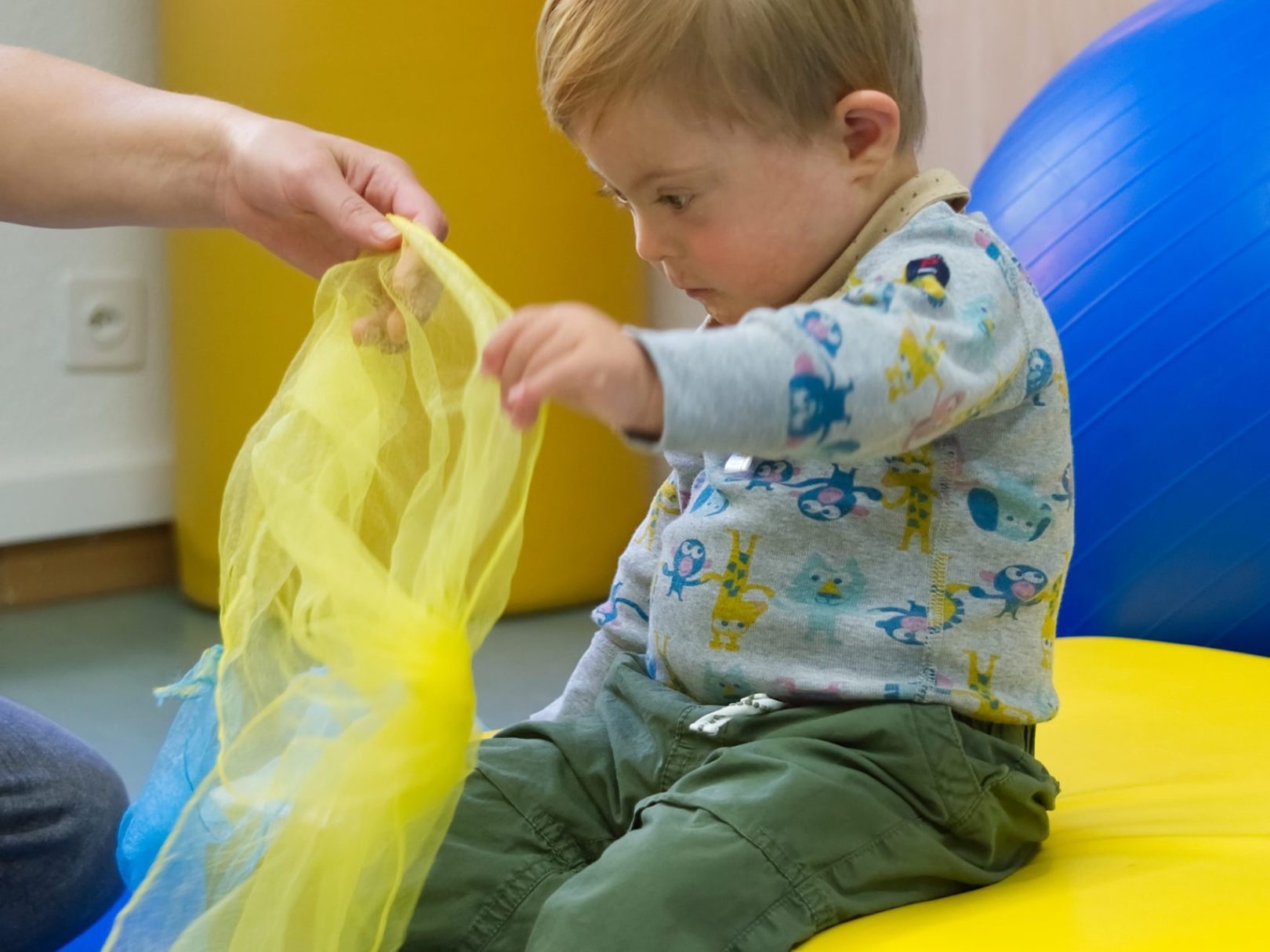 Ein kleiner Junge hält ein gelbes Tuch in der Physiotherapie.