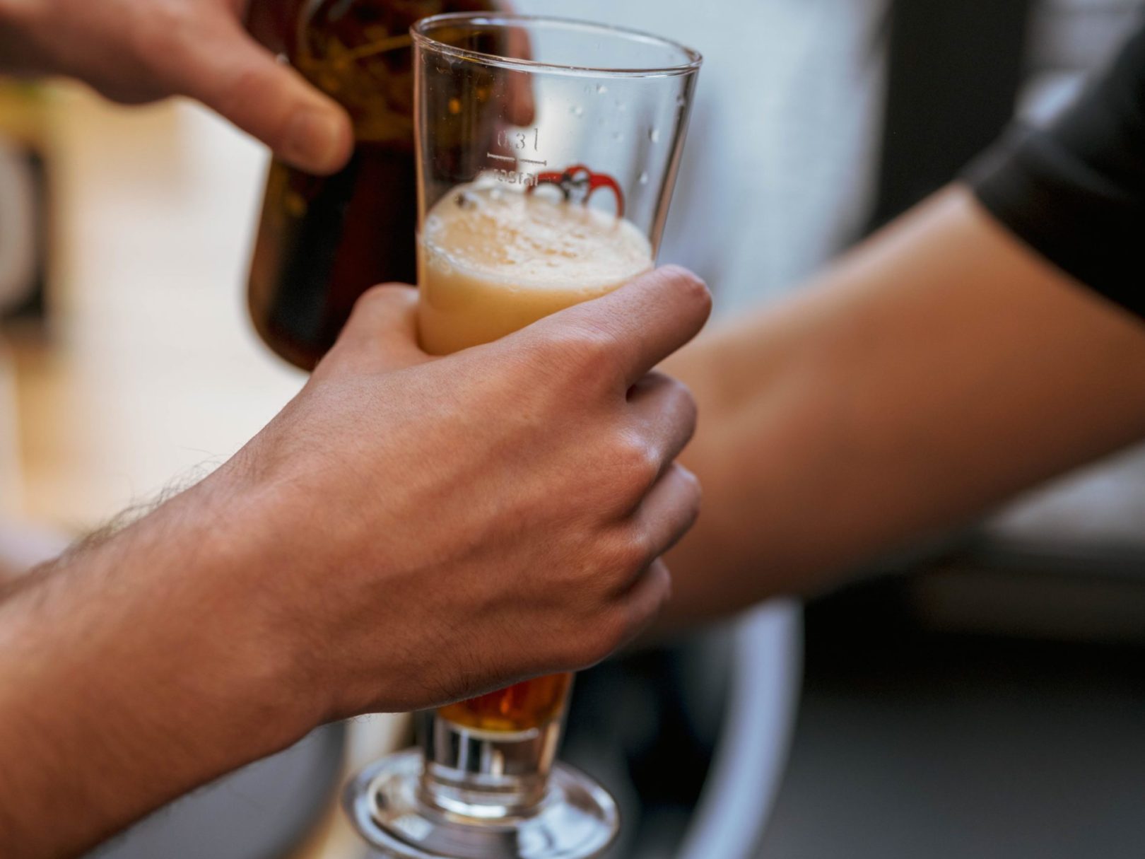 Ein Mann hält ein volles Bierglas und eine Flasche in den Händen.