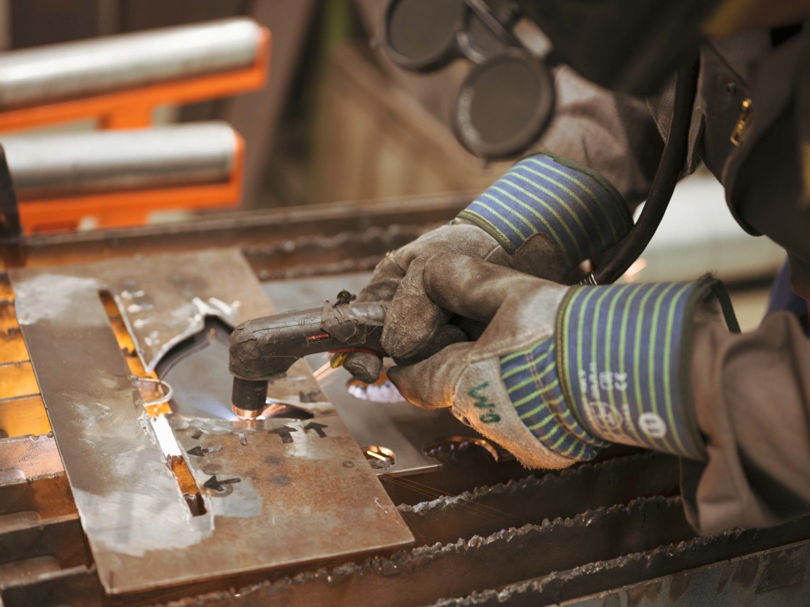 Eine Person mit Schutzhandschuhen schweisst Metall in der Werkstatt.