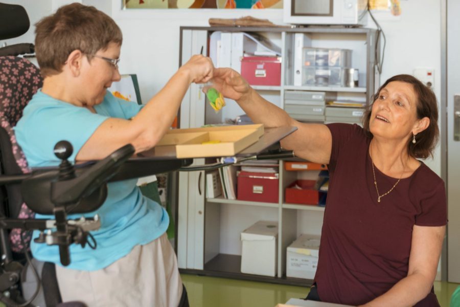 Eine Mitarbeiterin im Atelier spielt mit einer Person