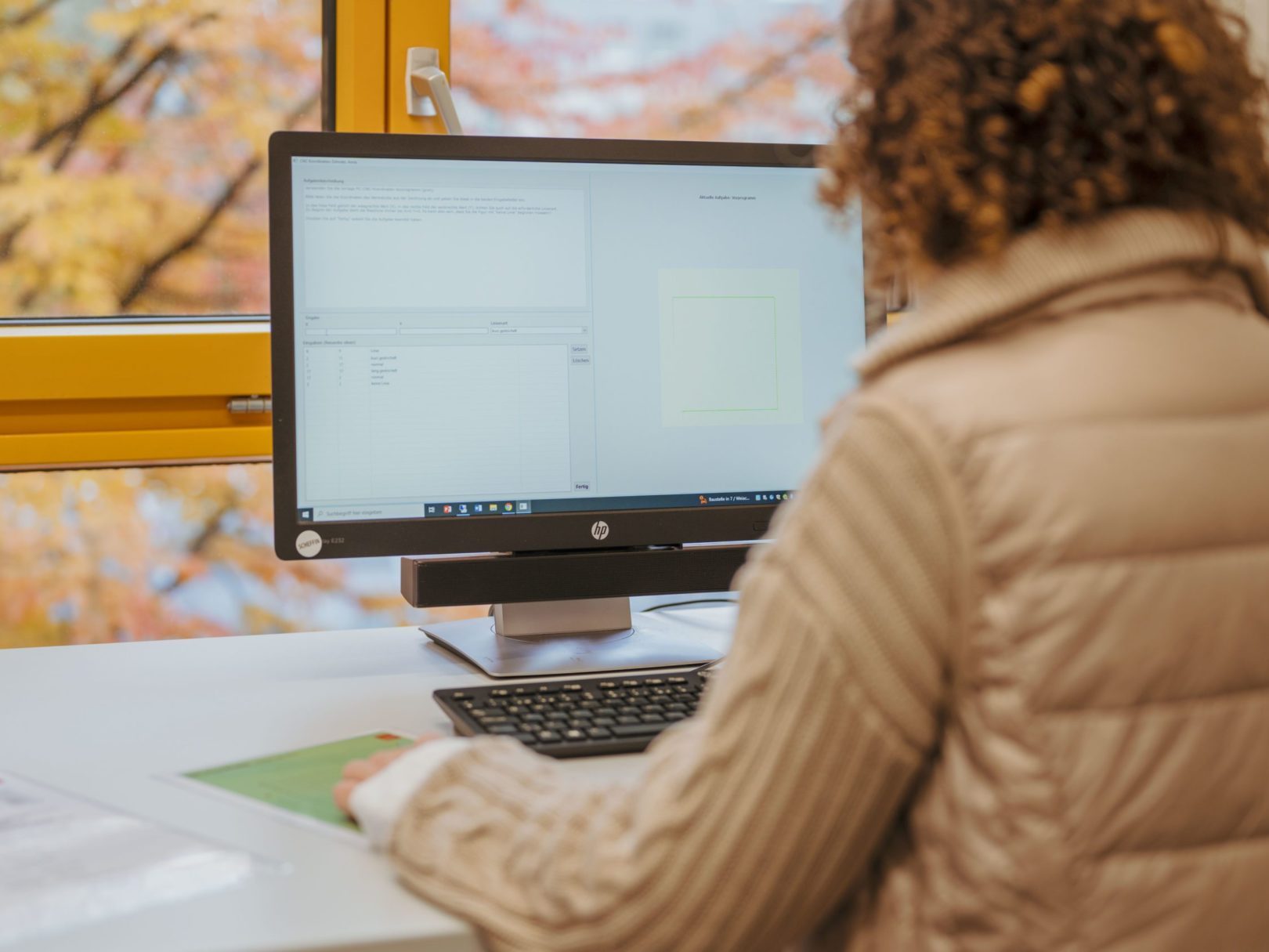 Eine Frau sitzt an einem Schreibtisch und arbeitet am Computer.