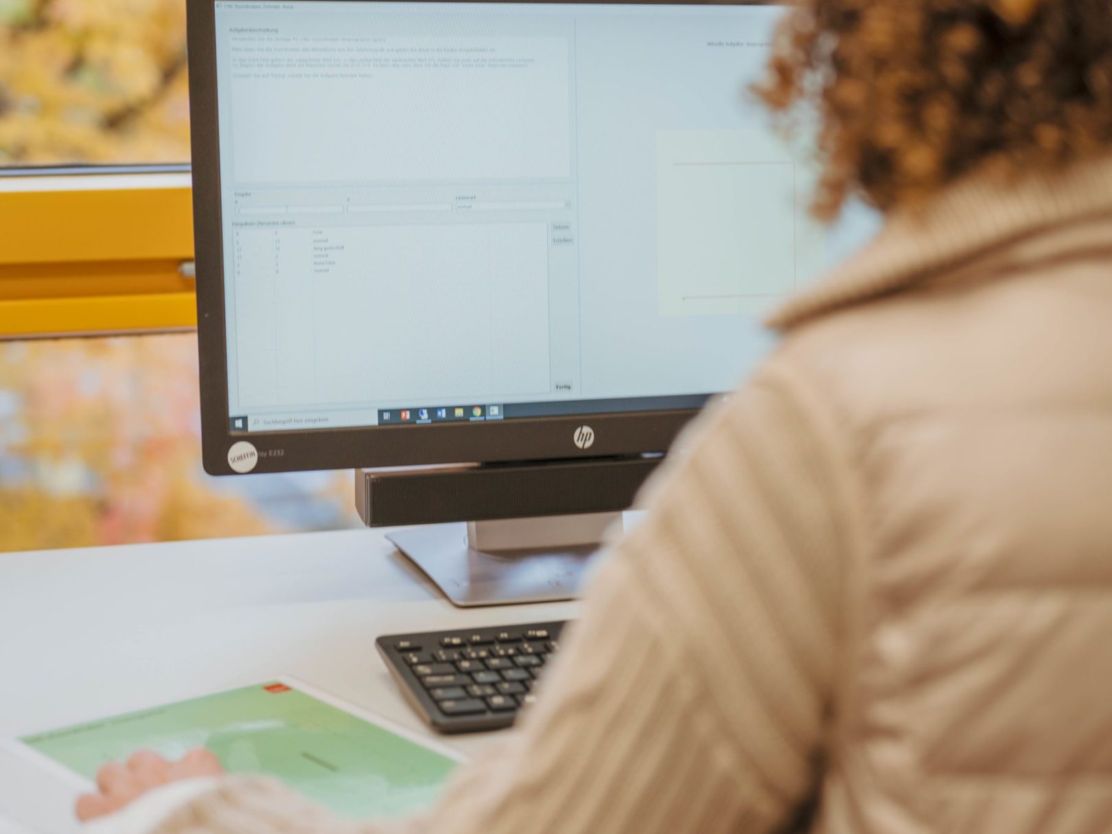 Eine Frau sitzt an einem Schreibtisch und arbeitet am Computer.