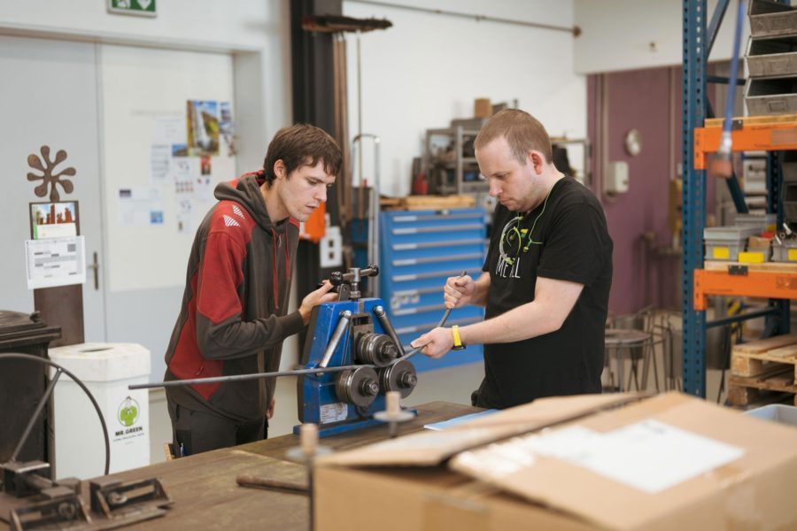 Zwei Männer arbeiten in einer Werkstatt an einer Maschine.