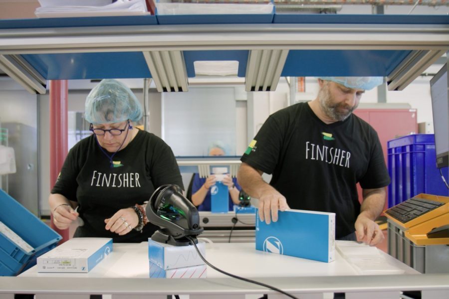 Zwei Personen arbeiten mit Verpackungen in einer Fabrik.