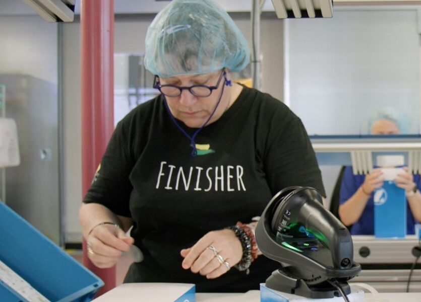 Zwei Personen arbeiten mit Verpackungen in einer Fabrik.