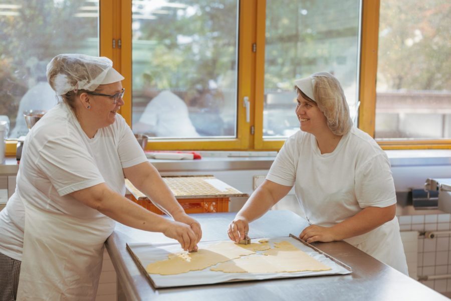 Zwei Frauen stehen mit Bäcker Hüten in der Brühlgut Bäckerei und stechen Kekse aus.