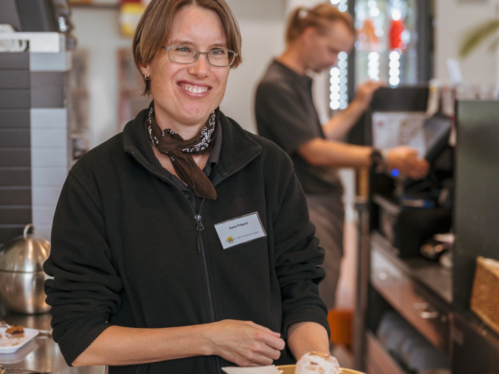 Eine Frau im Café Wyden hält ein Teller mit einem Gebäck in die Kamera.