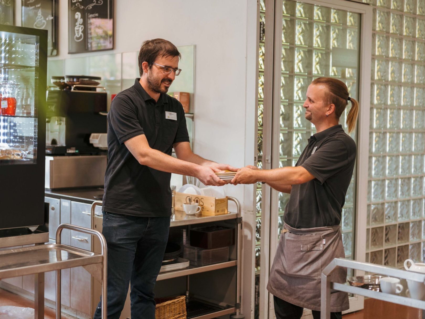 Zwei Angestellte im Café Wyden übergeben sich einen Stapel mit frisch gewaschenen Untertellern.