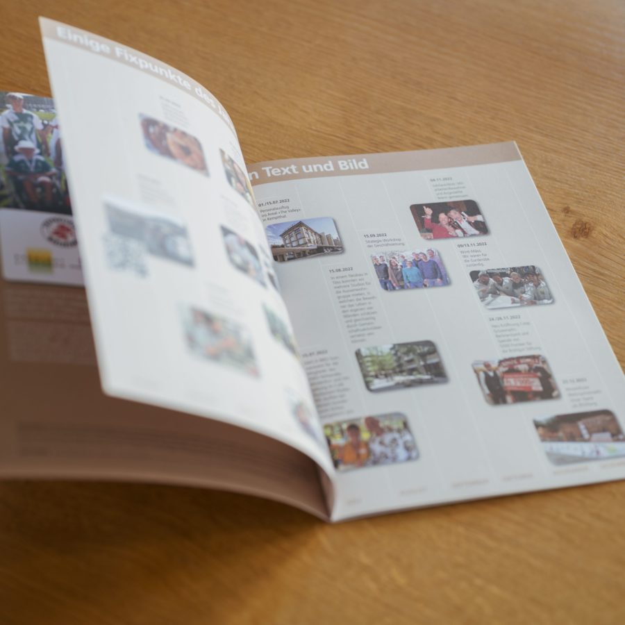 Eine Publikation der Brühlgut Stiftung mit Text und Bild liegt aufgeschlagen auf einem Holztisch.