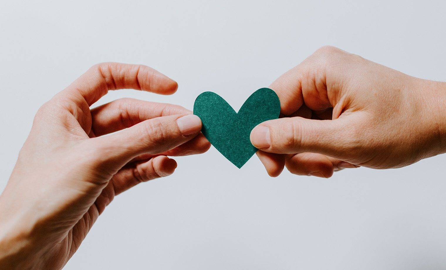 Zwei Hände halten ein Herz aus Papier