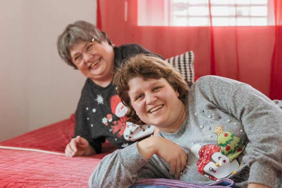 Zwei Bewohnerinnen der Aussenwohngruppe liegen auf einem Bett und lachen.