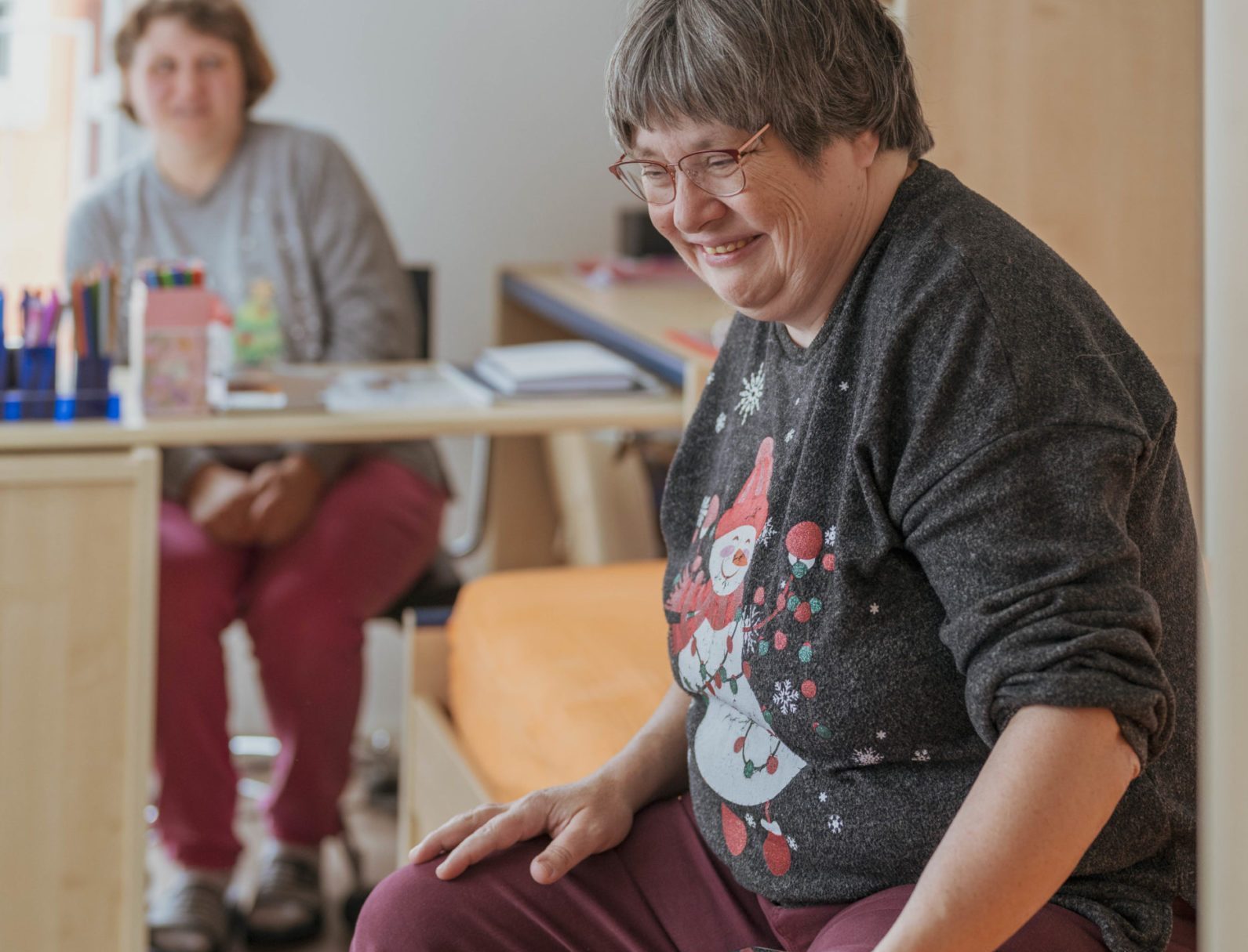 Zwei Bewohnerinnen der Aussenwohngruppe sitzen in einem Aufenthaltsraum und beschäftigen sich mit einem Tablet.