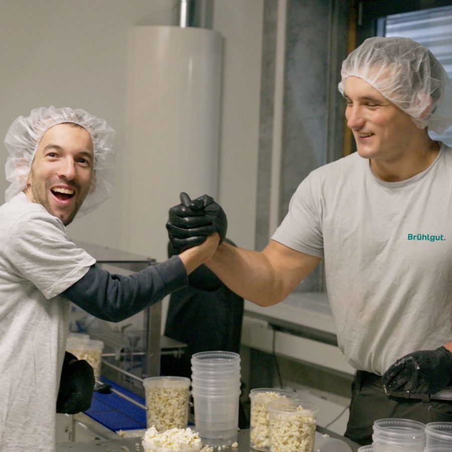 Zwei Männer machen Popcorn und klatschen sich mit den Händen ab.