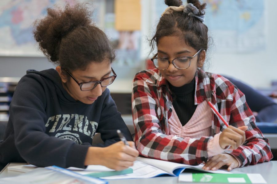 Zwei Kinder sitzen zusammen in der Schule und lösen eine Aufgabe