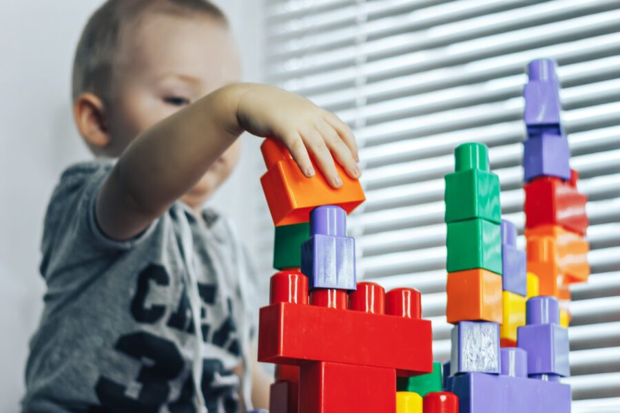 Ein Kind spielt am Tisch mit bunten Plastikbausteinen.